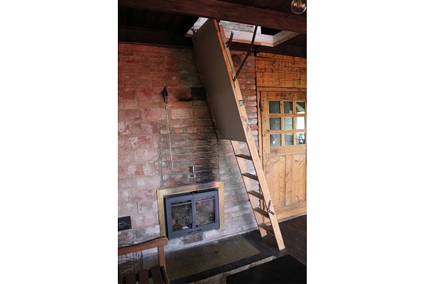Koka kāpnes un kamīns koka mājas interjerā