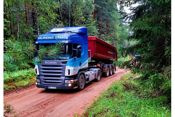Scania kravas automašīna pārvadā grants pa meža ceļu